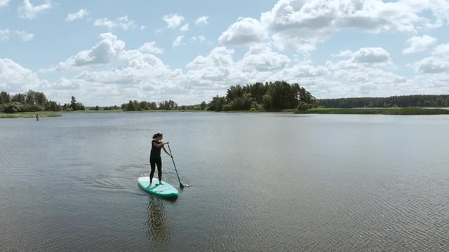 4k aerial. A women paddles on the center of the lake.