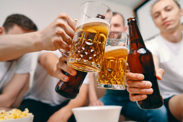 Friends watching Tv  while eating chips popcorn and drinking some cold beer