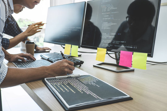 Two professional programmers cooperating at Developing programming and website working in a software develop company office, writing codes and typing data code