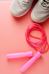 Sneakers, sport shoes and jumping rope over pink background. Health, running workout, fitness and yoga concept. Feminine background. Copy space.