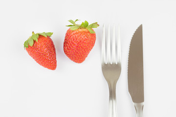 Fresh strawberry, fork and knife. White background.