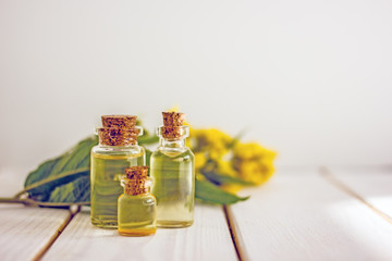 Transparent bottle with cork stopper with yellow oil on a background of wildflowers
