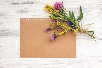 Flat lay frame mockup from a dark sheet of paper, wildflowers, herbs on a wooden background, copy space, top view