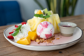 Crepe and ice cream with fresh fruit on wooden table.
