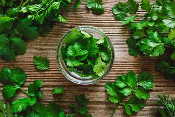 Glass Bowl of Cilantro with Loose Leaves on Wood Board