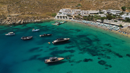 Aerial panoramic photo of famous turquoise clear sea celebrity sandy beach and bay of Psarou with yachts and sail boats in iconic island of Mykonos, Cyclades, Greece