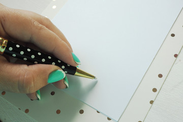 Female hand writes with a ballpoint pen on a clean sheet of paper on a clipboard..