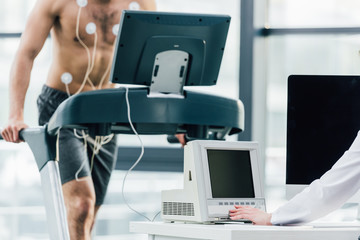cropped view of doctor conducting endurance test with sportsman in gym