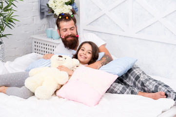 Obraz na płótnie Canvas Having fun pajamas party. Slumber party. Happy fatherhood. Close friends. Dad and girl relaxing in bedroom. Pajamas style. Father bearded man with funny hairstyle ponytails and daughter in pajamas