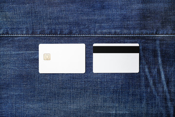 Two blank white plastic credit cards on denim background. Chip cards. Front and back view. Flat lay.