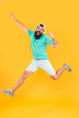 Fototapeta na wymiar Song of happiness. Bearded man jumping with happiness on yellow background. Happy hipster enjoy listening to music in modern headphones. Happiness frequency. Music for happiness and positive thinking