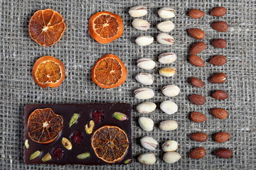 Dried orange slices, pistachios and almonds are laid out in rows on coarse linen fabric.