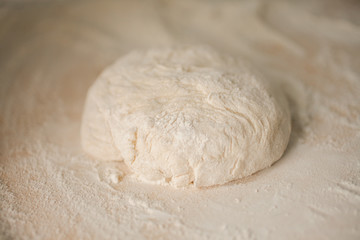 Ball of pizza dough on a rustic wooden background with dusting of flour