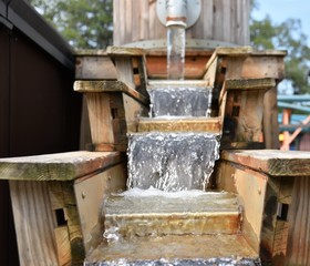 A barrel fountain with dropping steps represents recycled clean water in mining or sifting for fossils