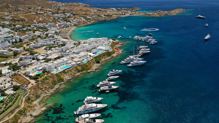 Aerial panoramic photo of famous turquoise clear sea celebrity sandy beach and bay of Psarou with yachts and sail boats in iconic island of Mykonos, Cyclades, Greece
