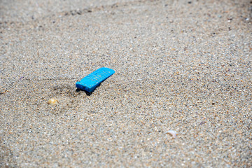 Fototapeta na wymiar blue microplastic in the sand of the beach