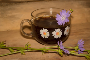 cup of chicory coffee and flowers on a wooden background