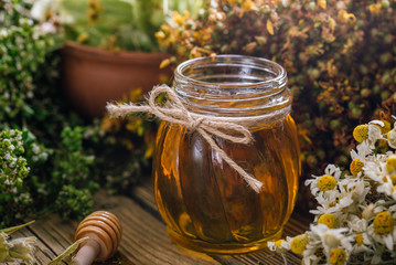Flower honey in a glass jar, harvesting wild medicinal herbs