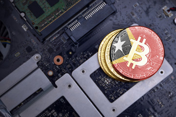 golden bitcoins with flag of east timor on a computer electronic circuit board. bitcoin mining...
