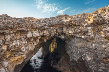 Big natural hole in the rock. Coral Lagoon in Mellieha. Kayak man. Malta