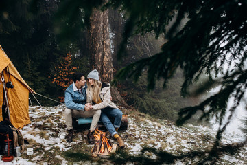 Portrait shot of th eyoungCaucasian couple sitting and huging at the tent in the middle of the...