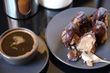 Anthill chocolate cake dessert on a gray plate and cup of coffee. Black table in the kitchen.