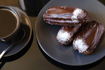 chocolate eclairs on a plate and cup of coffee. traditional fcench Chocolate Eclairs