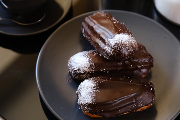 chocolate eclairs on a plate and cup of coffee. traditional fcench Chocolate Eclairs