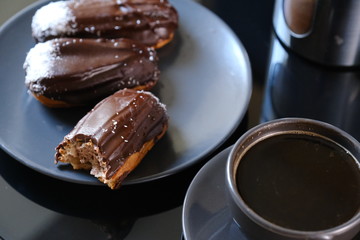 chocolate eclairs on a plate and cup of coffee. traditional fcench Chocolate Eclairs
