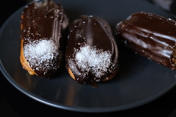 three chocolate eclairs on a plate on the table. french chocolate eclairs