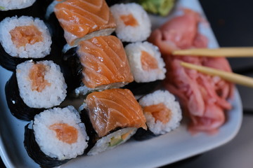 Sushi roll with seafood and soy sauce, wasabi and ginger. Sushi roll with salmon on a black background.