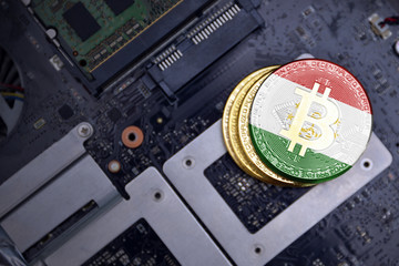 golden bitcoins with flag of tajikistan on a computer electronic circuit board. bitcoin mining...