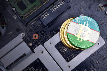 golden bitcoins with flag of uzbekistan on a computer electronic circuit board. bitcoin mining...