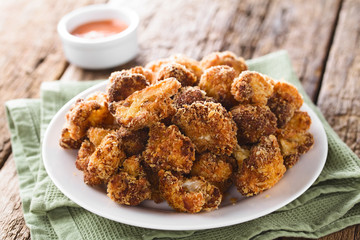 Fried breaded cauliflower florets on plate with fry sauce in the back (Selective Focus, Focus in the middle of the image)