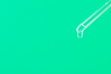 Serum for cosmetic procedures. Serum on a green background. Cosmetic pipette with a drop. Minimalism. Close up