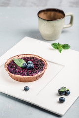 cake with blueberries and a Cup of coffee on light background