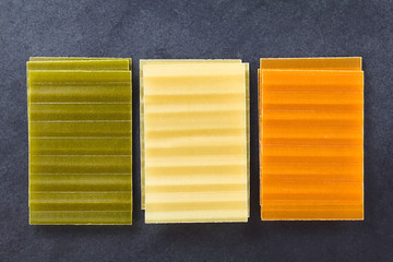 Raw tri color lasagne pasta sheets, photographed overhead on slate