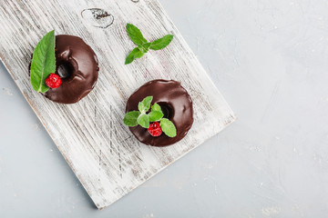 chocolate donuts with raspberries on a light background