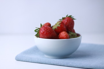 a bowl of strawbery on blue napkin
