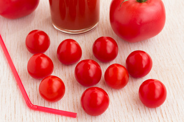 A glass of tomato juice and red tomatoes on a white background