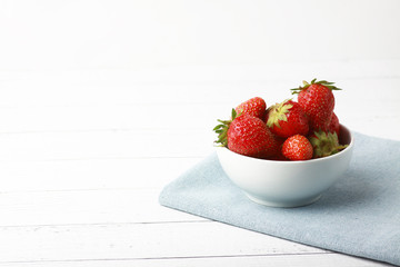 a bowl of strawbery on blue napkin isolated on white background.