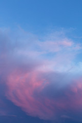 A mass of clouds swirls across the sky with vivid pink and blue colors at sunset.