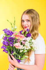 beautiful blonde girl with flowers looking at camera On yellow