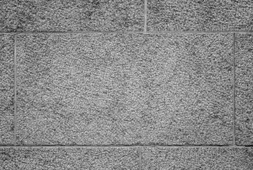 Close-up of part of a bumpy granite block stone wall in black and white with vignette. High resolution full frame background texture.