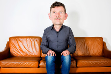 man with big head sitting on couch and waiting