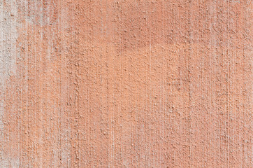 Close-up of plastered, painted, weathered, rough and red, orange or peachy concrete or stone wall. High resolution full frame textured background.