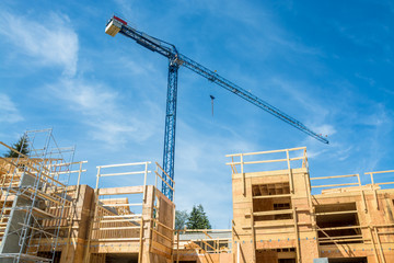 Crane above the new low-rise building under construction on sunny day in British Columbia, Canada
