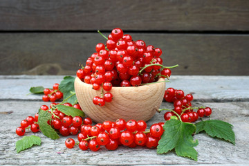  Red currants in a wooden bowl on a background of wooden boards