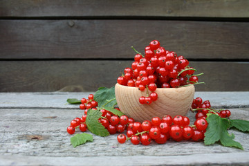  Red currants in a wooden bowl on a background of wooden boards