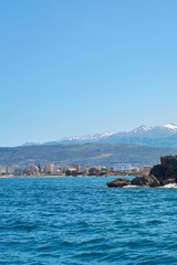  Sea coast with rocks in Chania, Crete, Greece with mountains and clear blue sky on a background.